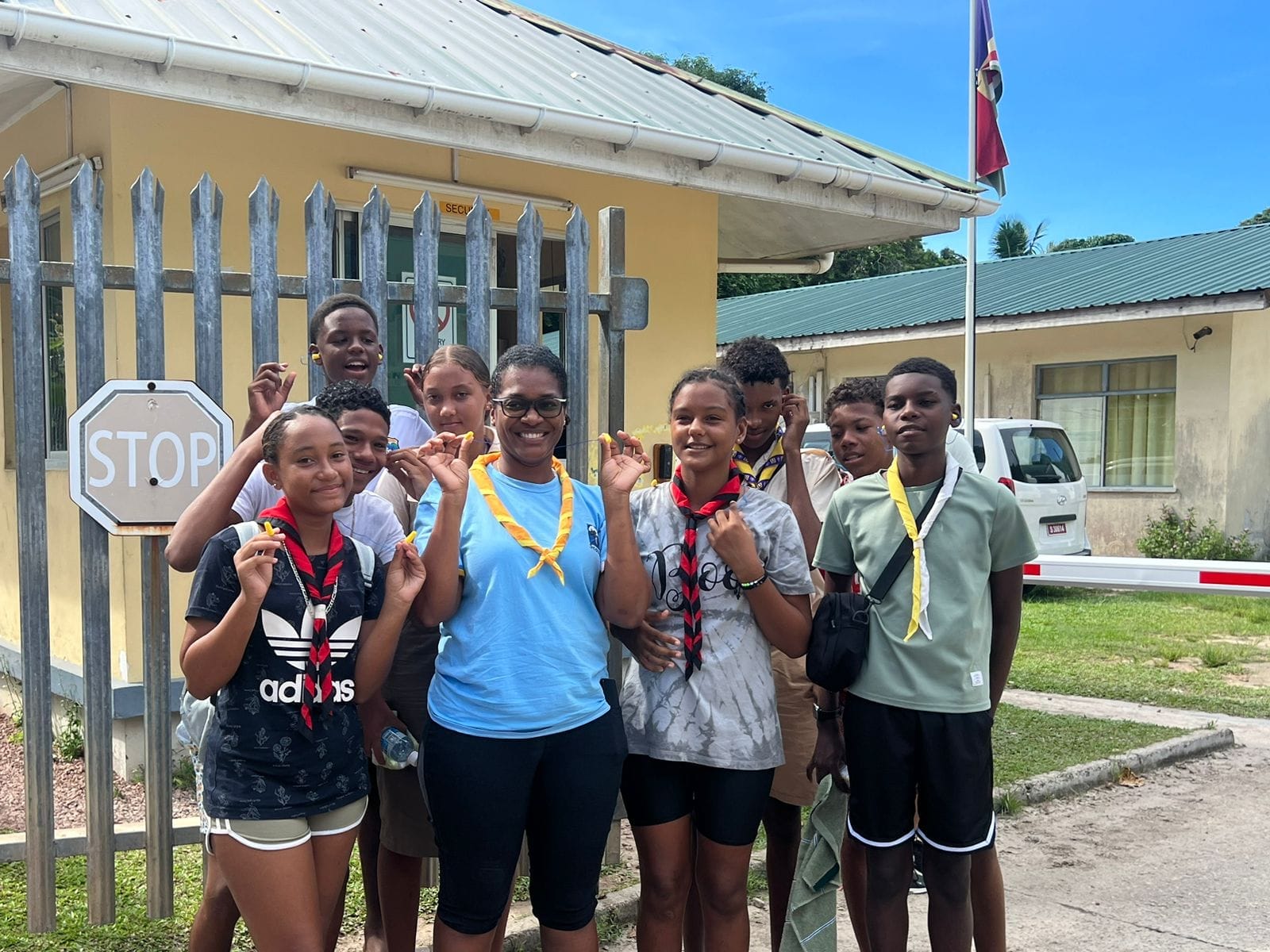 345051448_766556741666028_3661942203900715509_n Seychelles Scouts with their leader posing cheerfully by a stop sign during a community activity, showcasing their engagement and youthful enthusiasm.