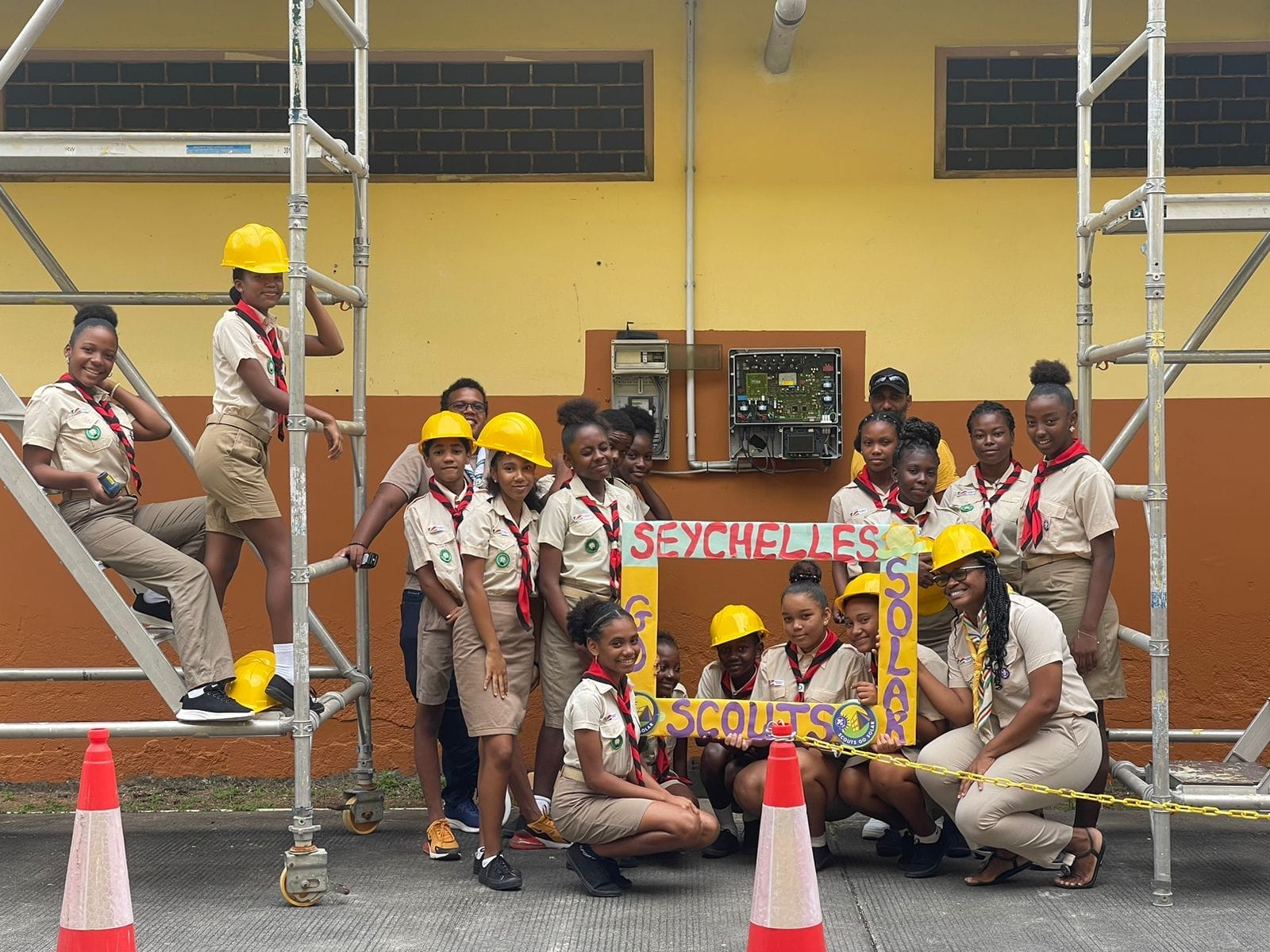 363390550_10233250448471819_505554073654679703_n Seychelles Scouts proudly displaying a 'Seychelles Solar Scouts' banner while posing on scaffolding at a solar energy training session, showcasing their active participation in renewable energy initiatives.
