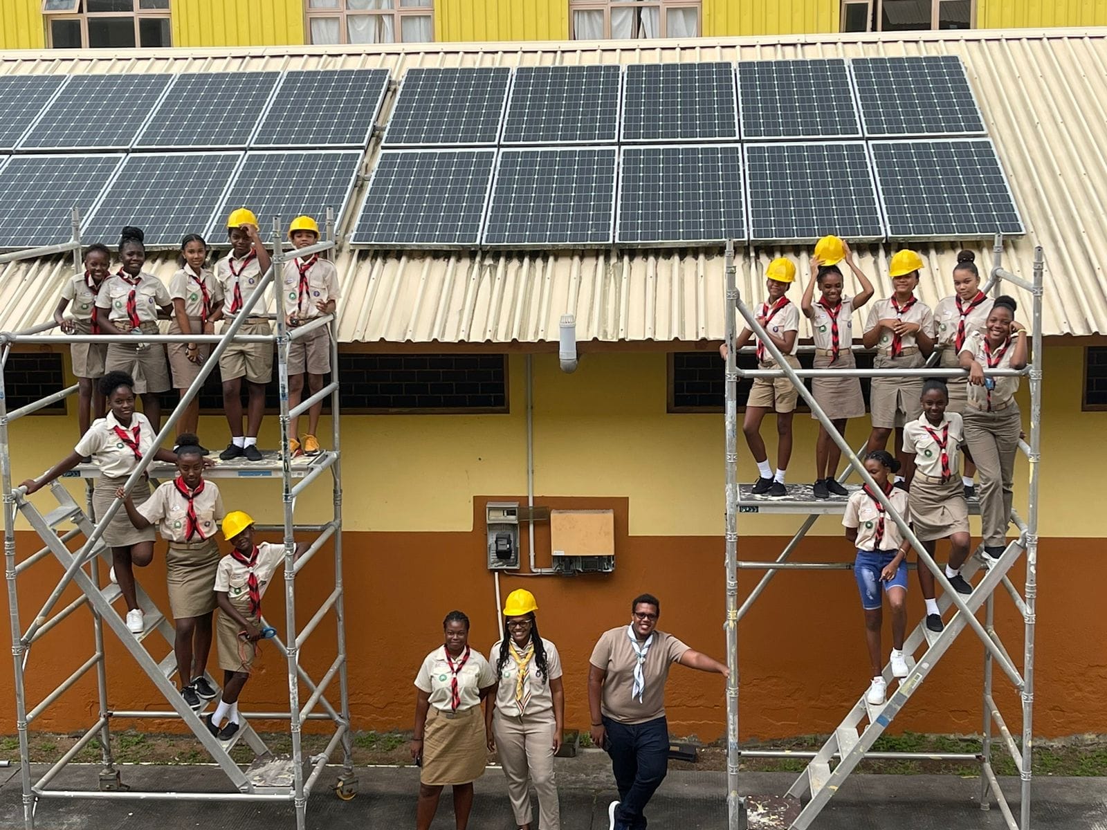 363417872_10233250451511895_3811414744571633563_n Seychelles Scout Association members standing on scaffolding in front of newly installed solar panels as part of a renewable energy project.