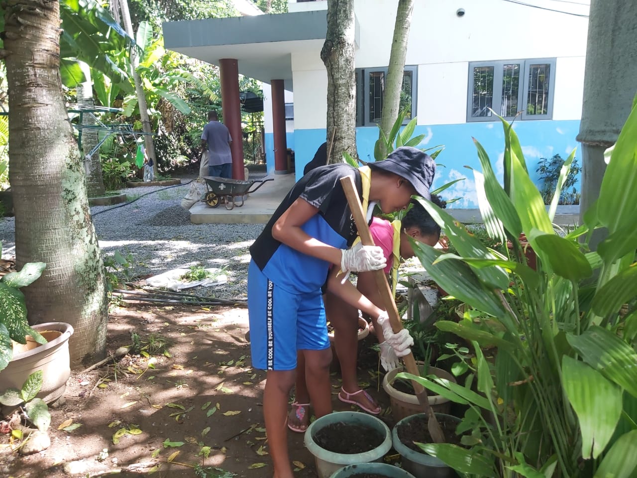 400989401_122123382602062808_5179159824978675417_n Scout members in Seychelles engaging in garden maintenance, cultivating plants and enriching their knowledge on eco-friendly practices in a lush green setting.
