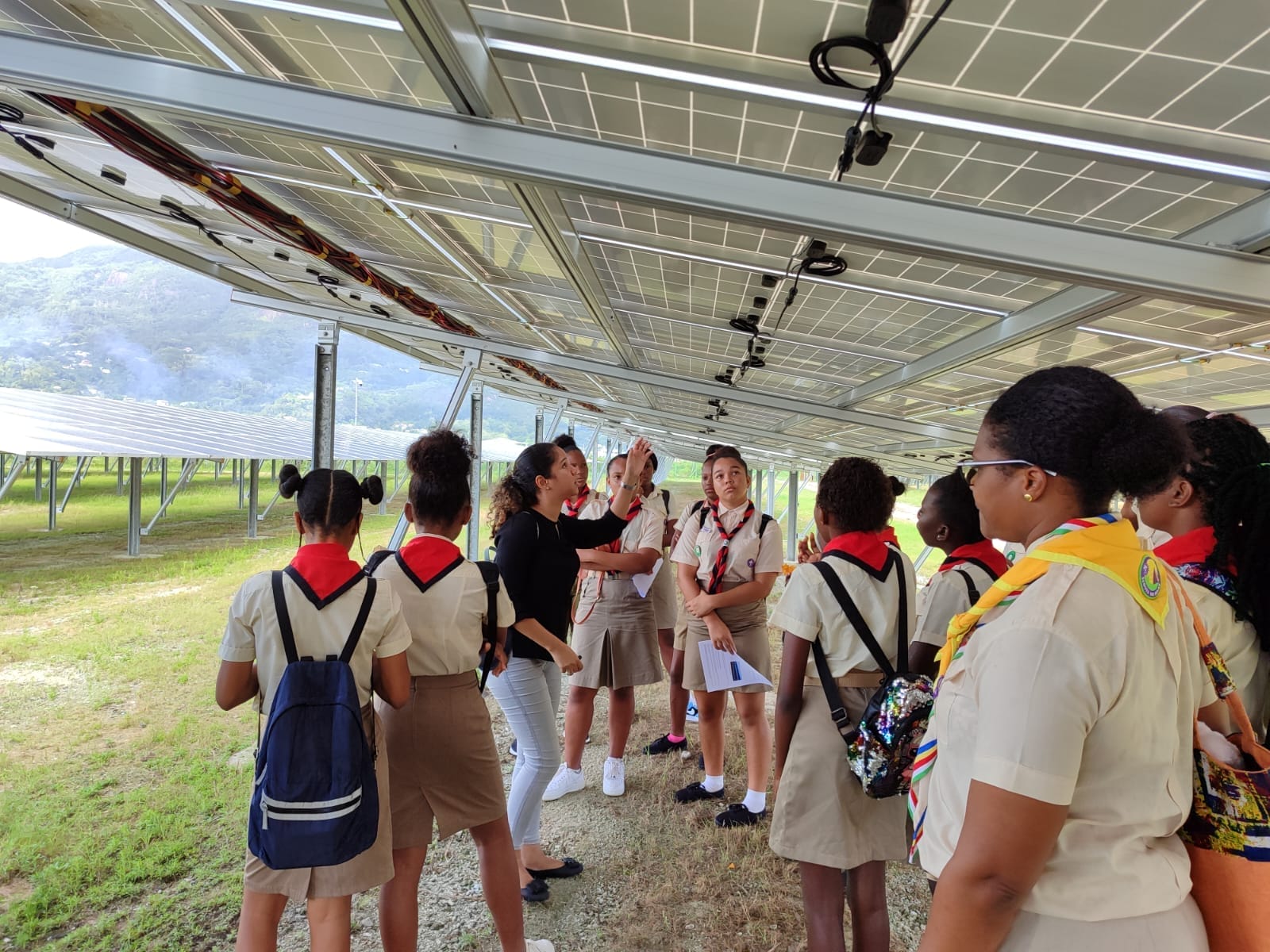 403826028_122125502090062808_3849129434507285879_n Seychelles scouts engaging in an educational session under solar panels, with a leader explaining the solar energy system, highlighting sustainability learning.