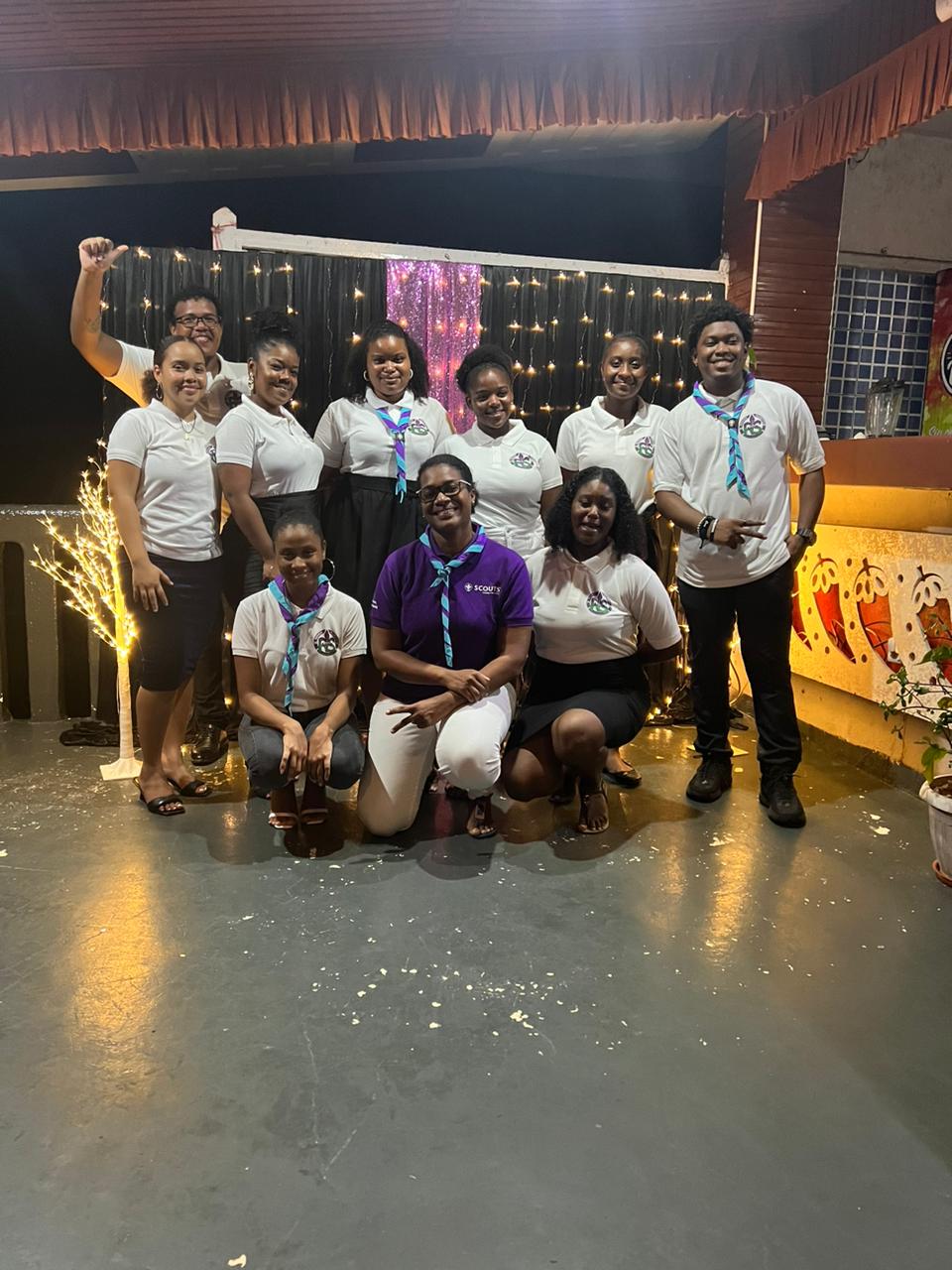 Group of joyful Rover Scouts in Seychelles posing at their gala event with festive decorations in the background, embodying community spirit and unity.